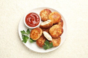 Tasty patties, parsley and ketchup on light textured table, top view