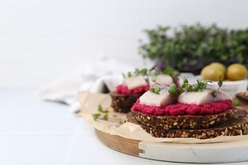 Tasty sandwiches with herring and horseradish sauce on white table, closeup. Space for text