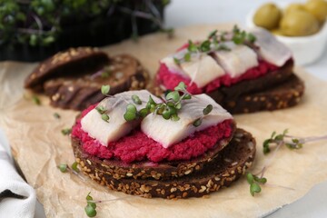 Tasty sandwiches with herring and horseradish sauce on table, closeup