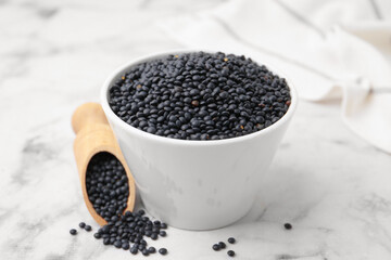 Black lentils on white marble table, closeup