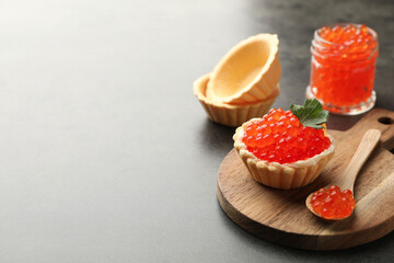 Tasty canape with red caviar, spoon and parsley on grey table, closeup. Space for text