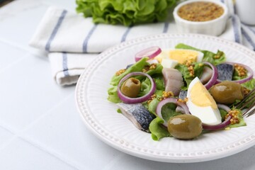 Delicious salad with herring, egg, mustard and vegetables on white tiled table, closeup