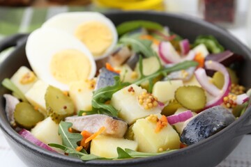 Delicious salad with herring, egg and vegetables in bowl on table, closeup