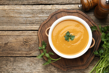Delicious lentil cream soup with parsley on wooden table, top view. Space for text