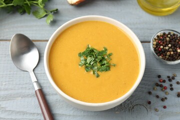 Delicious lentil cream soup with parsley served on grey wooden table, closeup