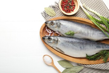 Salted herrings and spices on white wooden table, flat lay. Space for text