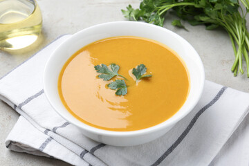 Delicious lentil cream soup with parsley and oil on light grey table, closeup
