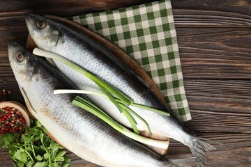 Salted herrings and spices on wooden table, flat lay. Space for text