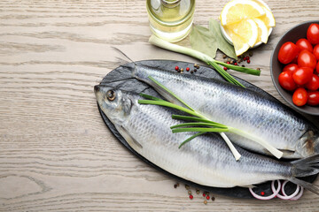 Salted herrings, spices and tomatoes on wooden table, flat lay. Space for text