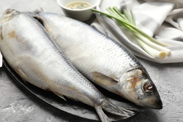 Salted herrings and green onions on grey table, closeup
