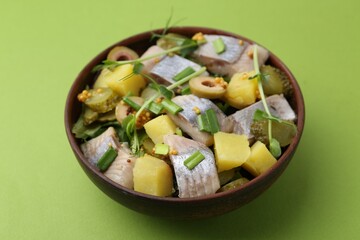 Delicious salad with herring on green background