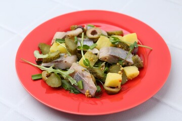 Delicious salad with herring on white tiled table, closeup