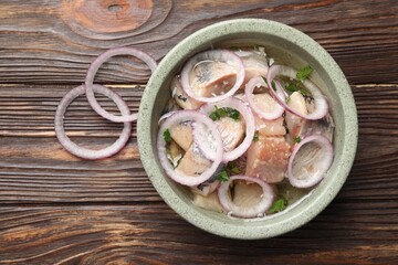 Pieces of delicious herring with onions on wooden table, top view