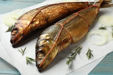 Smoked herrings, rosemary and onion on light blue wooden table, closeup