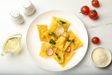 Delicious ravioli with microgreens, radish and other products on light table, flat lay