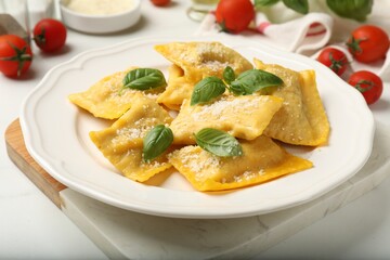 Delicious ravioli with cheese and basil served on white table, closeup