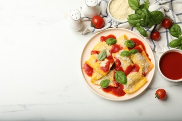 Delicious ravioli with tomato sauce, parmesan cheese and basil on white table, flat lay. Space for text