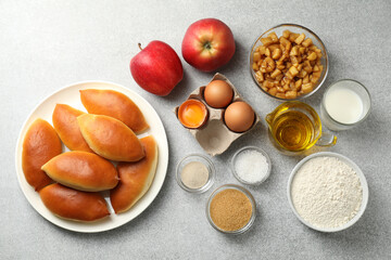 Tasty baked patties and ingredients on light grey table, flat lay