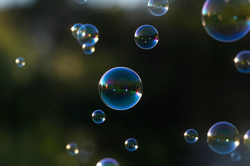 Naklejka premium Dreamlike soap bubbles floating in soft light with vivid reflections. Surreal and photorealistic atmosphere.