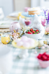 Easter table set up pink cups and bunny statue holding strawberries