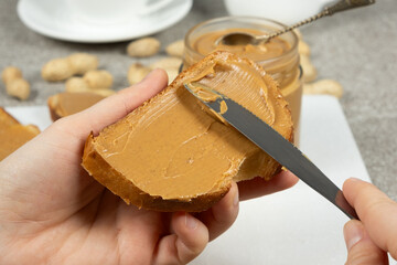 The process of spreading peanut butter on bread, hands close-up