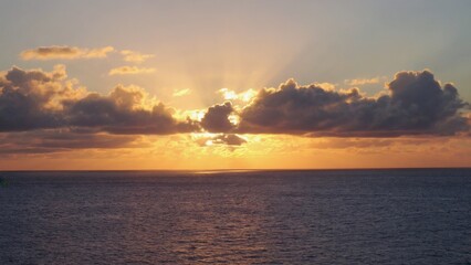 Calm sea at sunset with clouds scattered across the sky.
