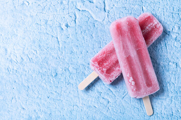 Red strawberry popsicles on blue background. Top view. Copy space