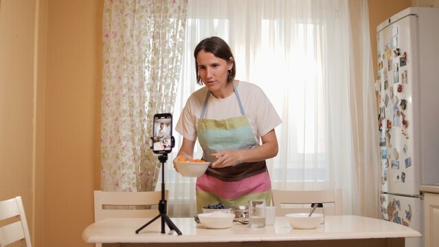 Food blogger recording cooking video using smartphone in kitchen