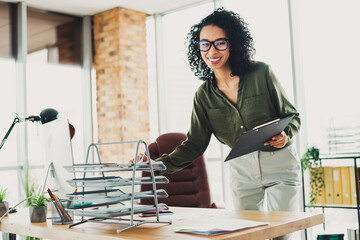 Confident businesswoman organizing a modern office workspace, showcasing professionalism and...