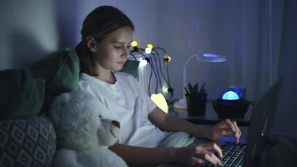 Cute Little Girl Typing On A Laptop In Bed Before Sleep, Surfing On The Internet