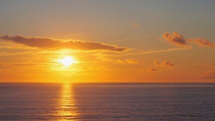 Fototapeta premium A tranquil sunset over the ocean with clear reflections on the water's surface. A beautiful end to a day at the beach.