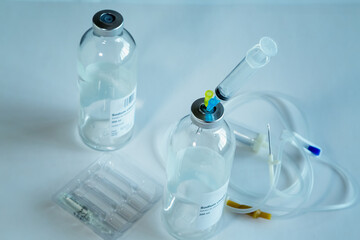 A medical syringe with needles for injections inserted into a dropper bottle, and nearby empty dropper catheters and bottle on a white background, used dropper bottle