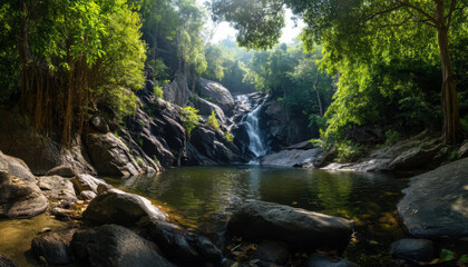 A peaceful waterfall flows into a crystal-clear pool, framed by vibrant tropical foliage and rocky terrain in Thailand’s forest