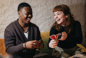 Friends laughing and playing cards in a cozy home environment, showcasing happiness, connection, and shared enjoyment.