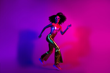 Glamorous young woman dancing with a neon glowing background showcasing retro fashion and positive...