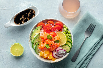 Poke bowl with salmon. Hawaiian salad with rice, fish, tomato, and avocado. Healthy diet. Overhead flat lay shot with a drink