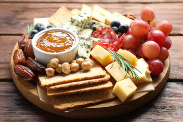 Different types of delicious cheese and other snacks on wooden table, closeup