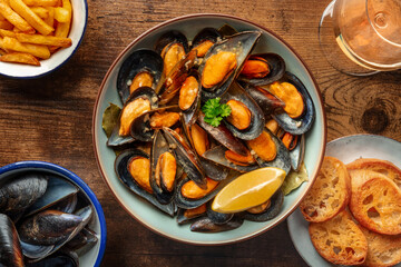 Mussels with French fries, white wine, and toast, moules frites, with lemon, shot from the top on a...