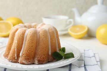 Delicious lemon cake with glaze and mint on white table, closeup