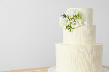 Delicious wedding cake with floral decor on table against white background, closeup. Space for text