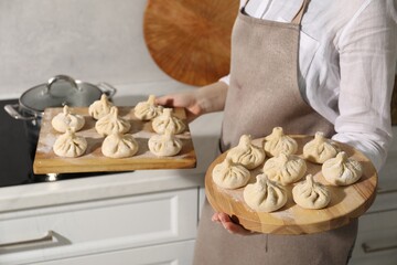 Fototapeta premium Woman with many uncooked khinkali in kitchen, closeup