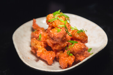 Chicken fillet in sweet and sour sauce garnished with herbs on a plate