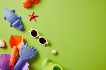 Kids beach toys and sunglasses flat lay on bright green background. Summer vacation concept with copy space. Top view children's accessories.