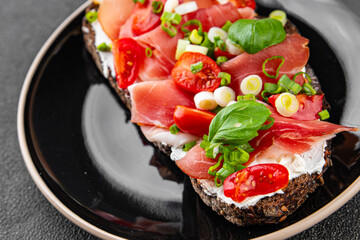 Bruschetta ham, tomato, greens dish fresh delicious gourmet food background on the table rustic food top view copy space