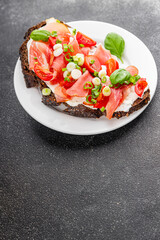 Bruschetta ham, tomato, greens dish fresh delicious gourmet food background on the table rustic food top view copy space