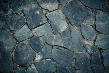Fototapeta premium Close-up view of textured gray slate stones arranged in a natural pattern. Ideal for backgrounds, landscaping, and outdoor designs, showcasing earthy tones.