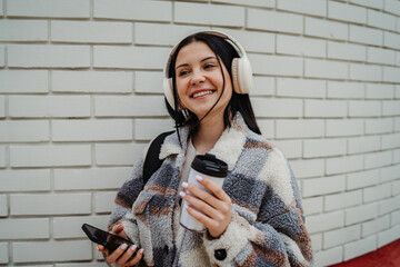 Portrait of a teenage girl student smile and listen to music on wireless headphones