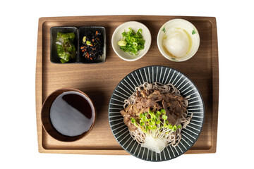 Japanese soba noodle set with sauced pork, grated daikon, microgreens, dipping sauce, hot spring egg, and side dishes served on a wooden tray from top view.