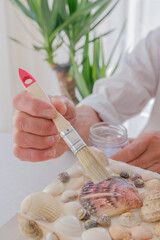 Elderly person varnishing seashell jewelry box with paintbrush