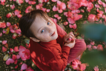 Child Smiling Among Vibrant Pink Flower Petals